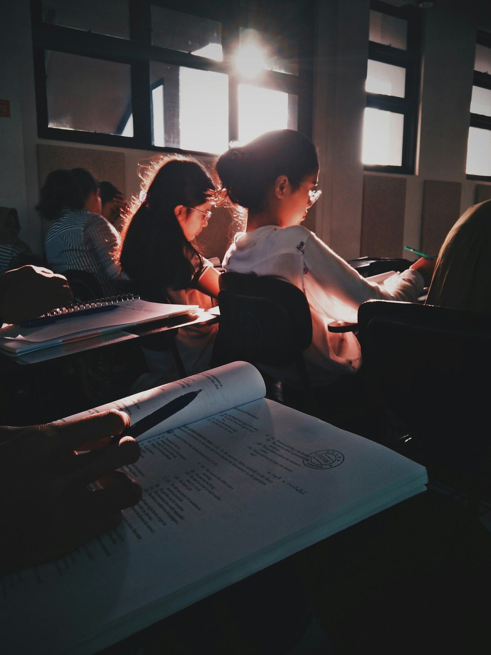 Étudiants dans une salle de classe lumineuse lisant des manuels pour préparer un examen